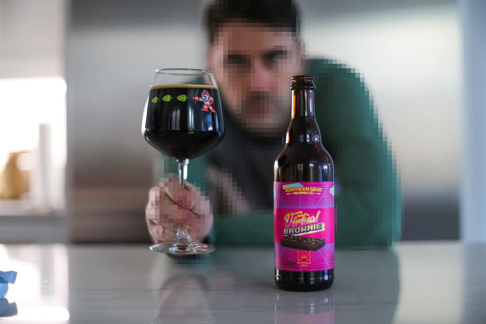 Doug, himself artificially pixelated, holds a glass of Virtual Brownie beer next to a bottle of the same